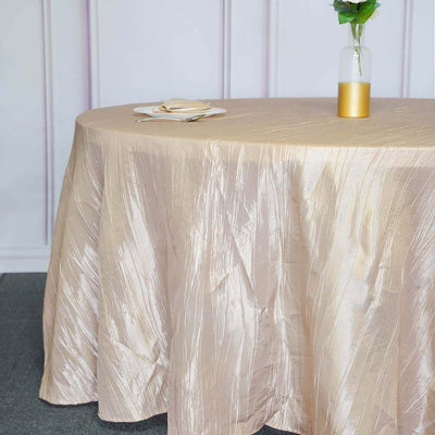 Elegant gold tablecloth draped over a round table with a vase and plates.
