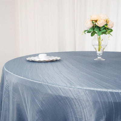 Elegant gray tablecloth with a vase of roses and decorative plate on a round table.
