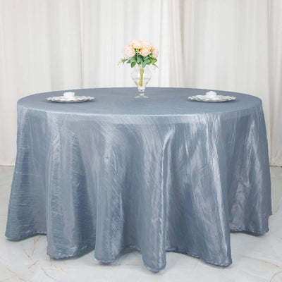 Round gray tablecloth draped over a table with a vase of flowers and plates.