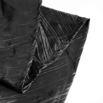Black textured fabric with intricate patterns and folds.