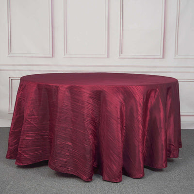 Burgundy tablecloth draped over a round table in a studio setting.