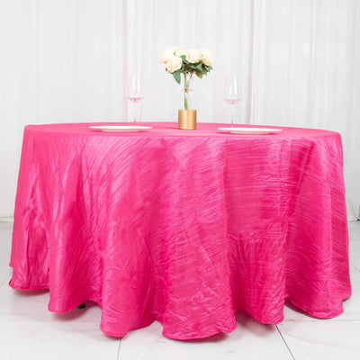 Pink tablecloth draped over a round table with floral centerpiece and wine glasses.