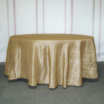 Gold round tablecloth draped on an oval table against a light backdrop.
