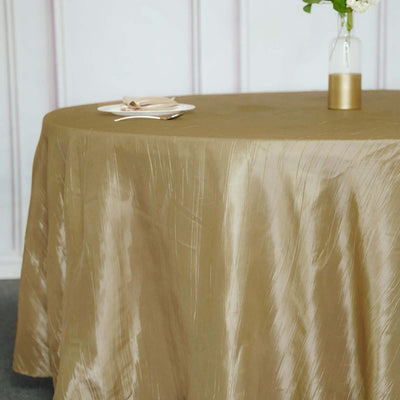 Elegant gold tablecloth draped over a round table with plates and a vase.