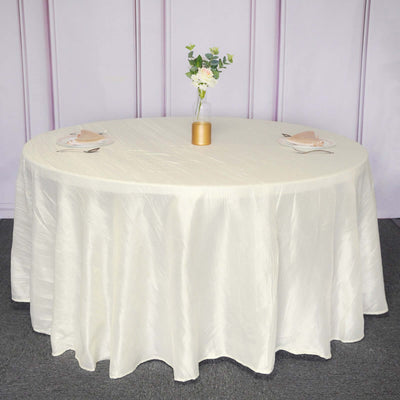 Round cream tablecloth draped over a circular table with floral centerpiece.