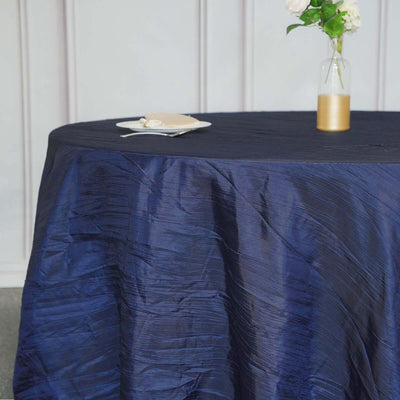 Navy blue textured tablecloth draped over a round table with a vase and plate
