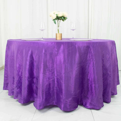 Purple tablecloth draped elegantly over a round table with floral centerpiece.
