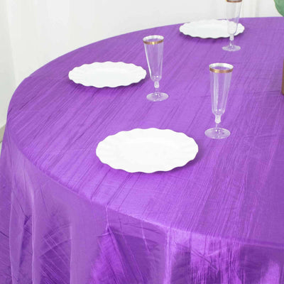 Purple tablecloth with white plates and clear glasses set for dining.