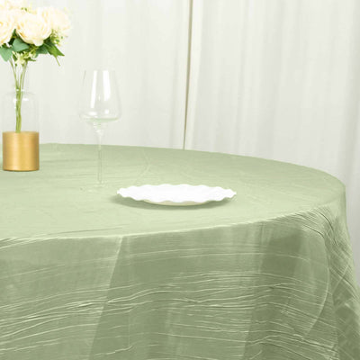 Elegant green tablecloth with a white plate and glass on a round table.