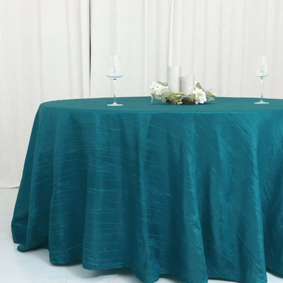 Teal tablecloth draped over a round table with decorative centerpiece