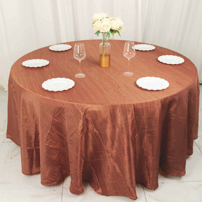 Round brown tablecloth with white plates and a floral centerpiece.