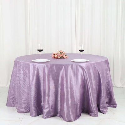 Round lavender tablecloth draped over a table with wine glasses and flowers.