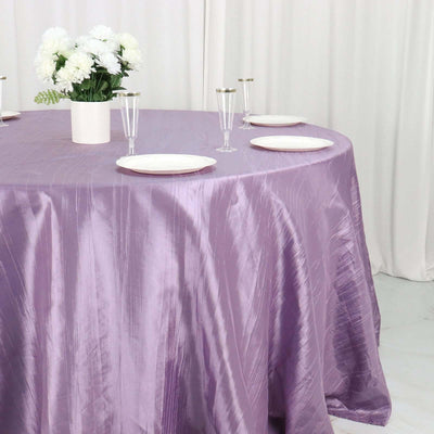 Purple tablecloth draped elegantly over a round table with plates and glasses.