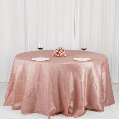 Round pink tablecloth with wine glasses and a flower centerpiece.