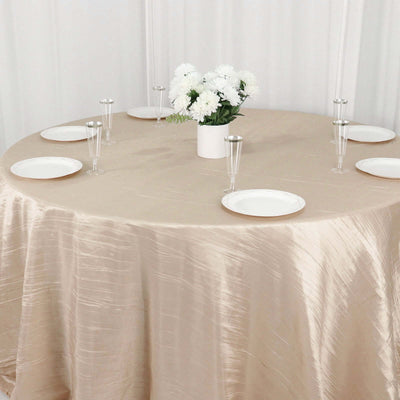 Elegant round table set with a beige tablecloth, plates, and floral centerpiece.