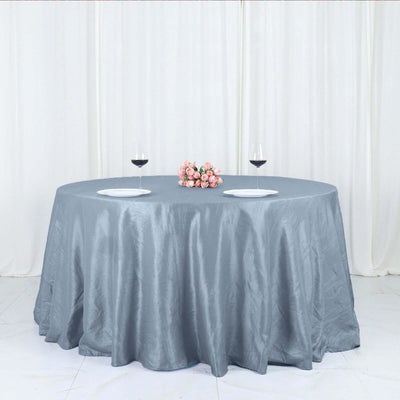 Elegant grey tablecloth on a round table with wine glasses and flowers.