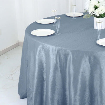Elegant gray tablecloth draping over round table with plates and glasses.