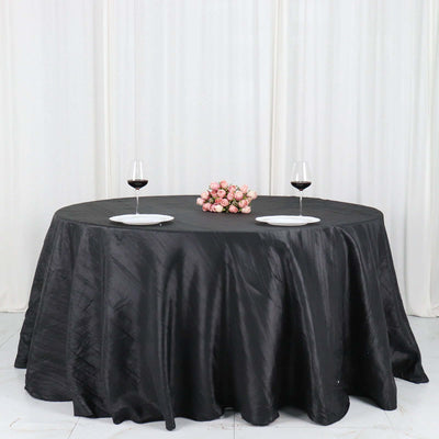 Elegant black tablecloth draped over a round table with wine glasses and floral centerpiece.