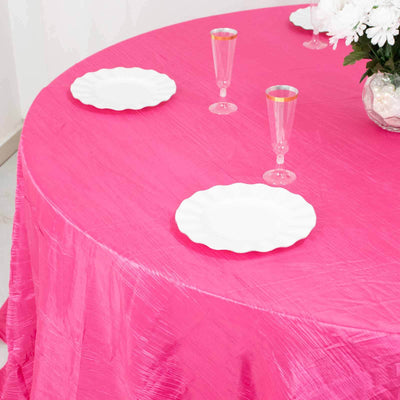 Pink tablecloth with white plates and glasses set for a dining experience.