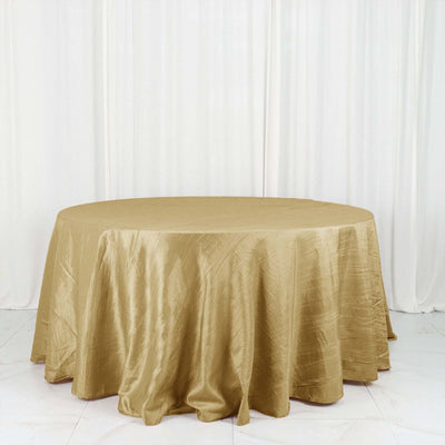 Round gold tablecloth draped over a circular table in a studio setting.