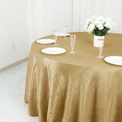 Gold tablecloth draped elegantly over a round table with plates and glasses.