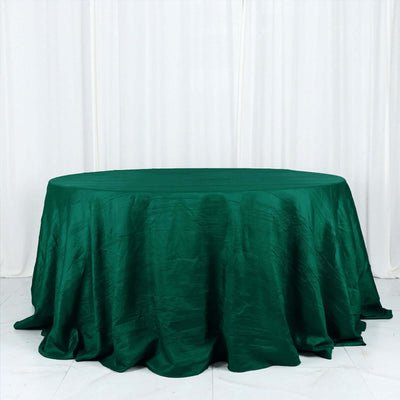 Green satin round tablecloth on a plain backdrop.