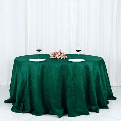Elegant green tablecloth with wine glasses and floral centerpiece.