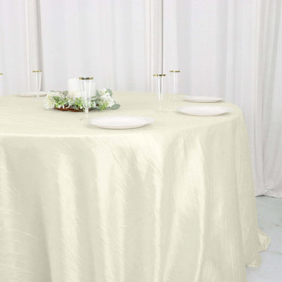 Elegant cream tablecloth draped over a round table with dinnerware and floral centerpieces.