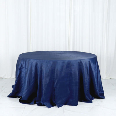 Navy blue round tablecloth with elegant draping on a plain backdrop