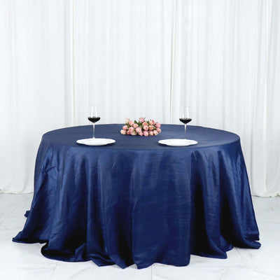 Round navy tablecloth draped elegantly with wine glasses and floral centerpiece.