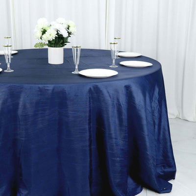 Navy blue tablecloth draped over a round table set for dining with floral centerpiece.