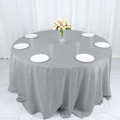 Round grey tablecloth with white plates and floral centerpiece.