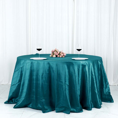 Elegant teal tablecloth with wine glasses and a floral centerpiece.