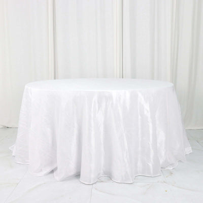 Round white tablecloth on a plain backdrop.
