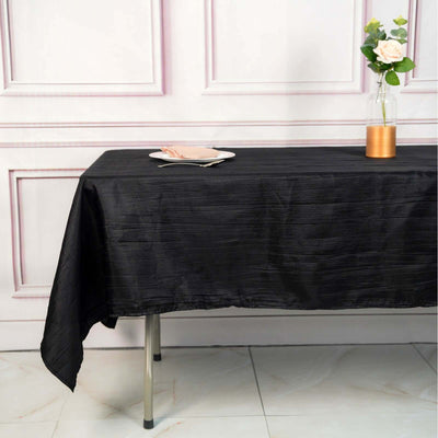 Black tablecloth draped over a table with a plate and flower vase