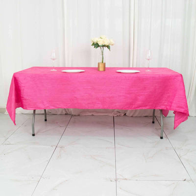 Pink tablecloth draped over a table with plates and a flower centerpiece.
