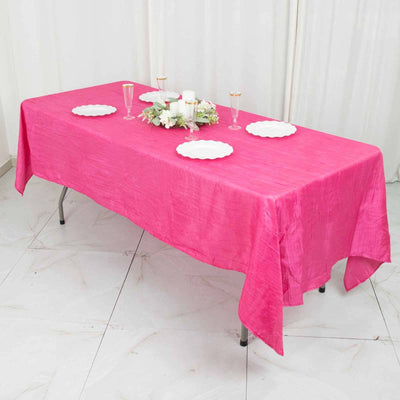 Bright pink tablecloth draped over a table, set with plates and decorative elements.