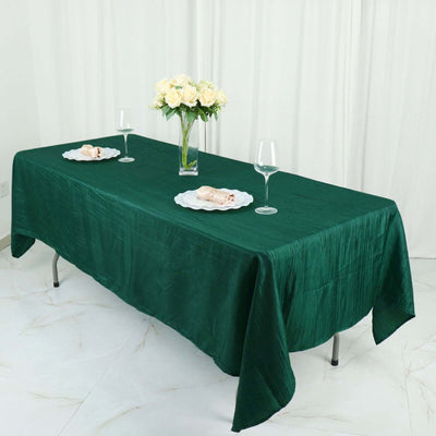 Elegant green tablecloth draped on a dining table with floral centerpiece.