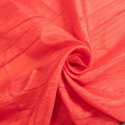 Coral-colored textured fabric, elegantly rolled.
