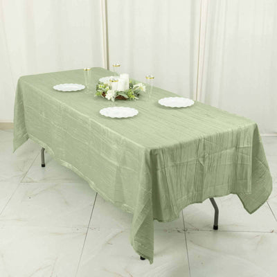 Green textured tablecloth draped over a table with white plates and candles.