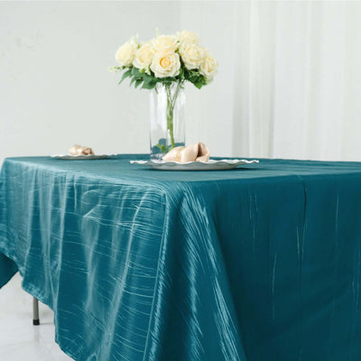 Teal tablecloth draped elegantly on a dining table with floral centerpiece.