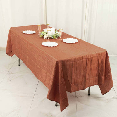 Rustic brown tablecloth draped over a table with decorative plates and candles.