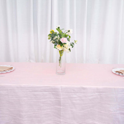 Floral centerpiece in glass vase on a pink tablecloth.