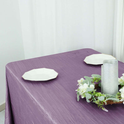 Purple tablecloth with decorative plates and a candle centerpiece.
