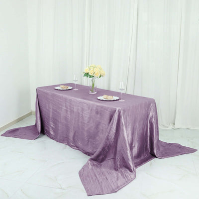 Elegant purple tablecloth draped over a table with flowers and plates.