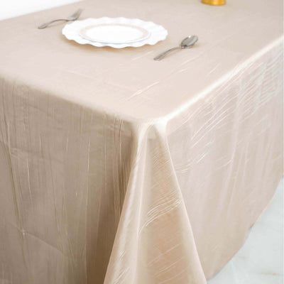 Elegant beige tablecloth draped over a table with a plate and cutlery.