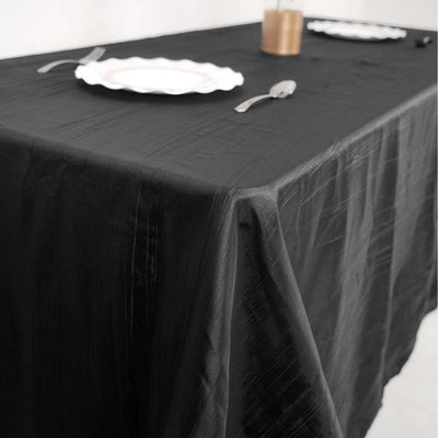 Black tablecloth draping a dining table with plates and cutlery.