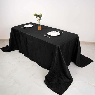 Black tablecloth draped elegantly over a dining table with plates and a vase.