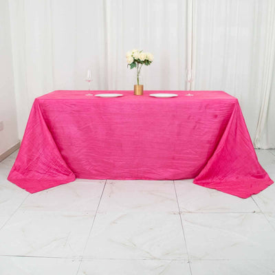 Pink tablecloth draped over a table with plates and flowers