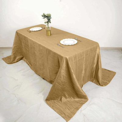 Elegant gold tablecloth draped over a table with plates and a vase.